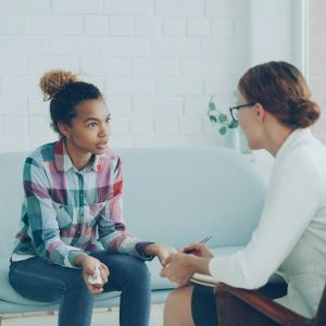 Therapist talking to a young woman on couch