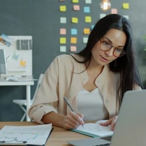 Woman working at a desk with laptop and notebook